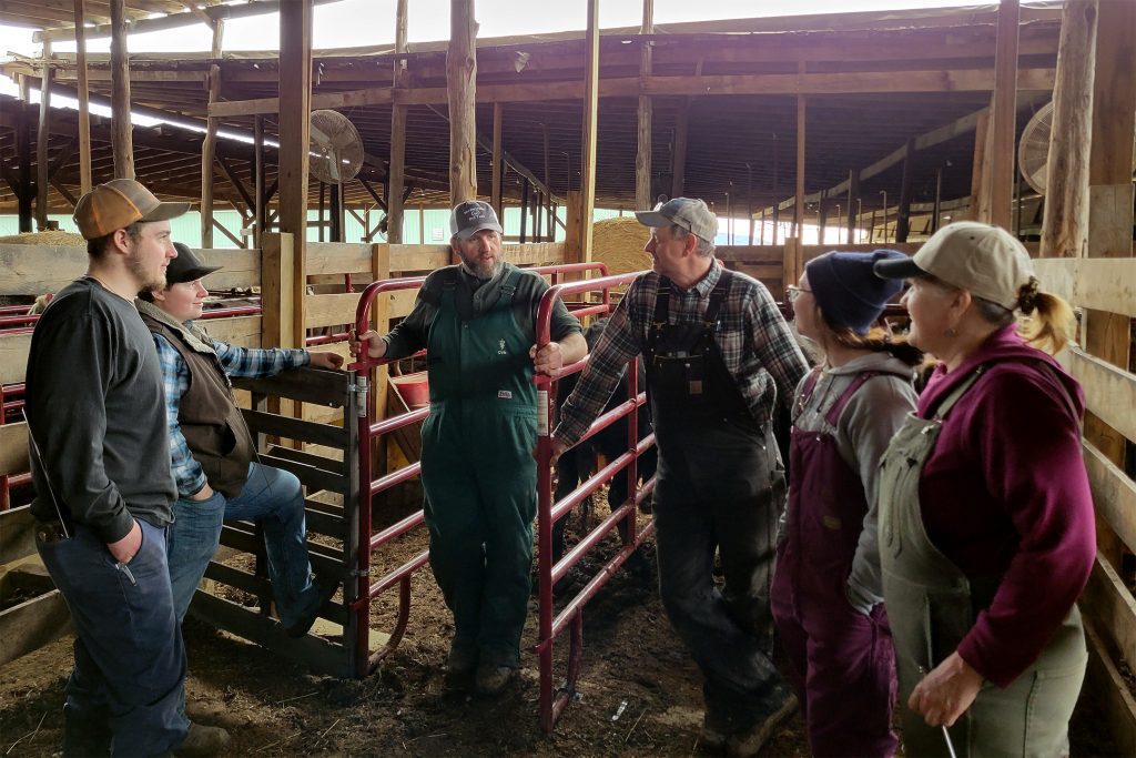 Photo of group of people talking in a stockyard.