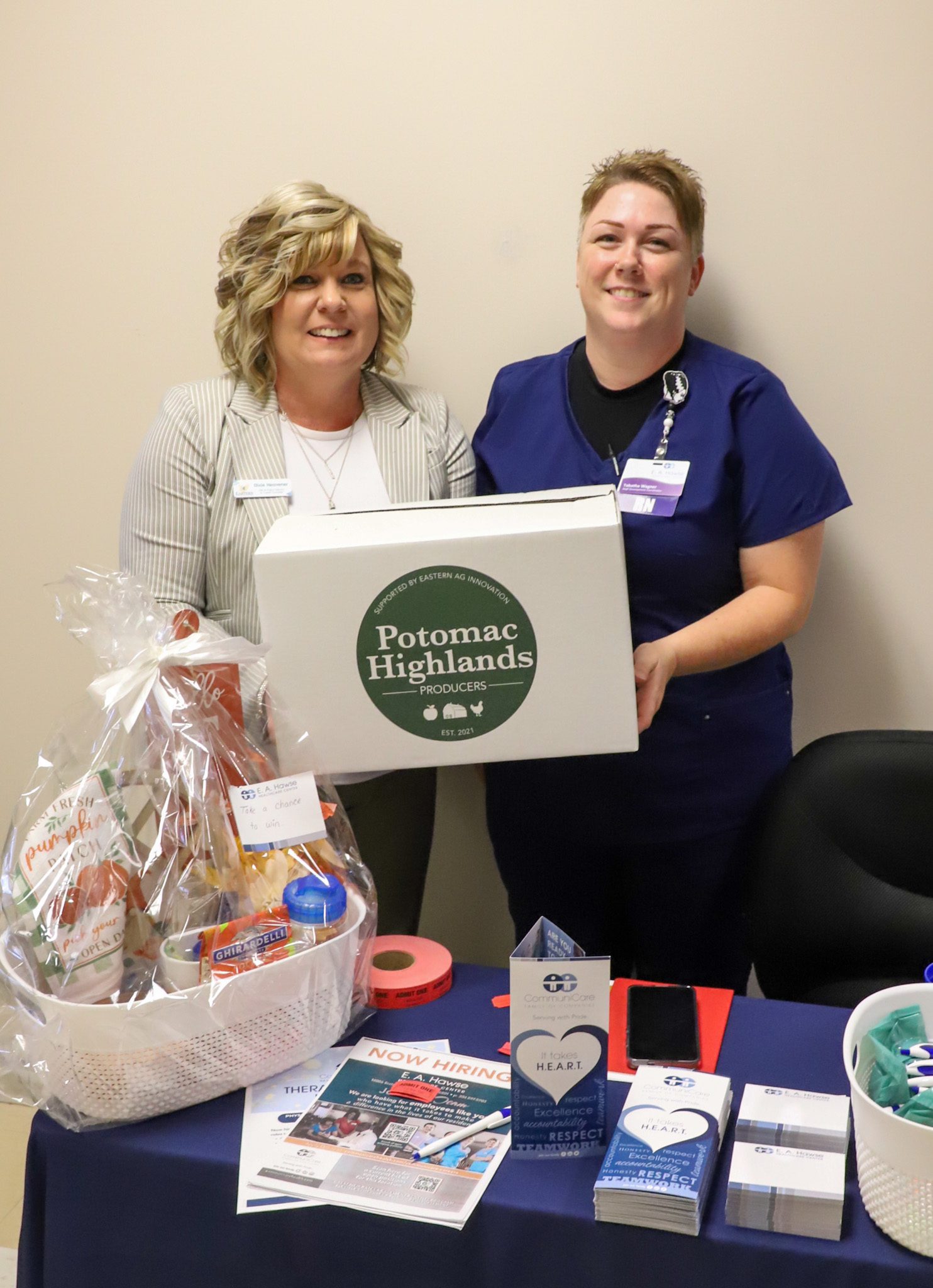 Portrait of two women holding a box, "Potomac Highlands Producers."