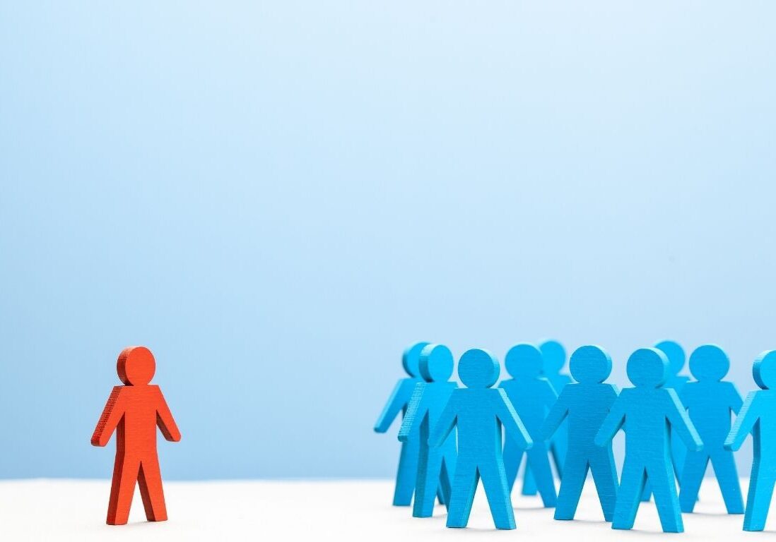 Photo of a red figure next to a group of blue figures.