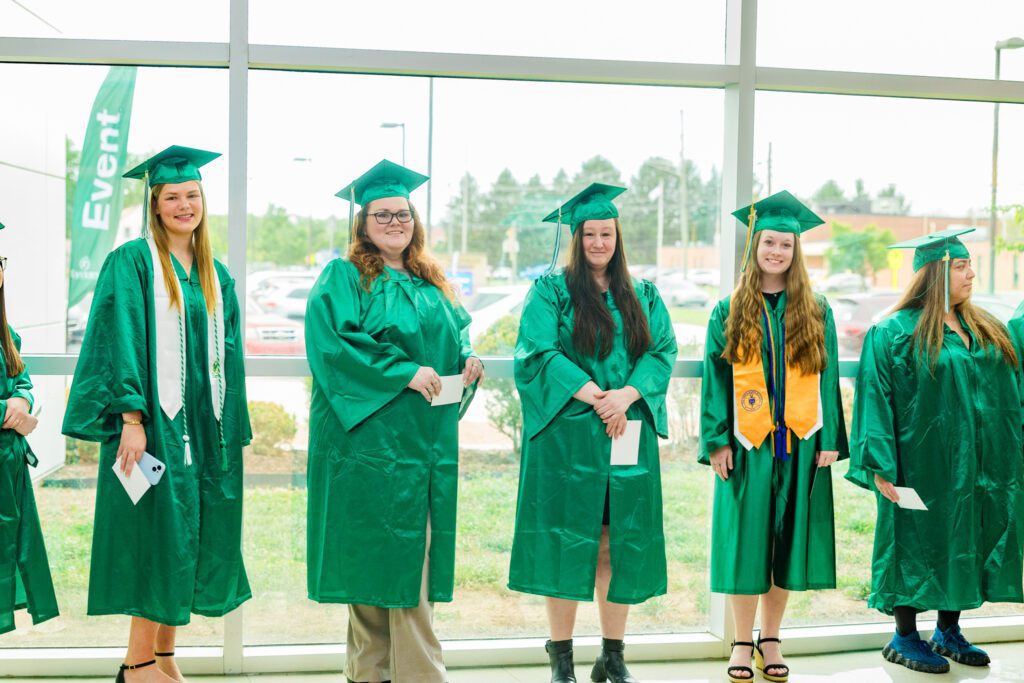 Photo of graduates lined up against large windows.