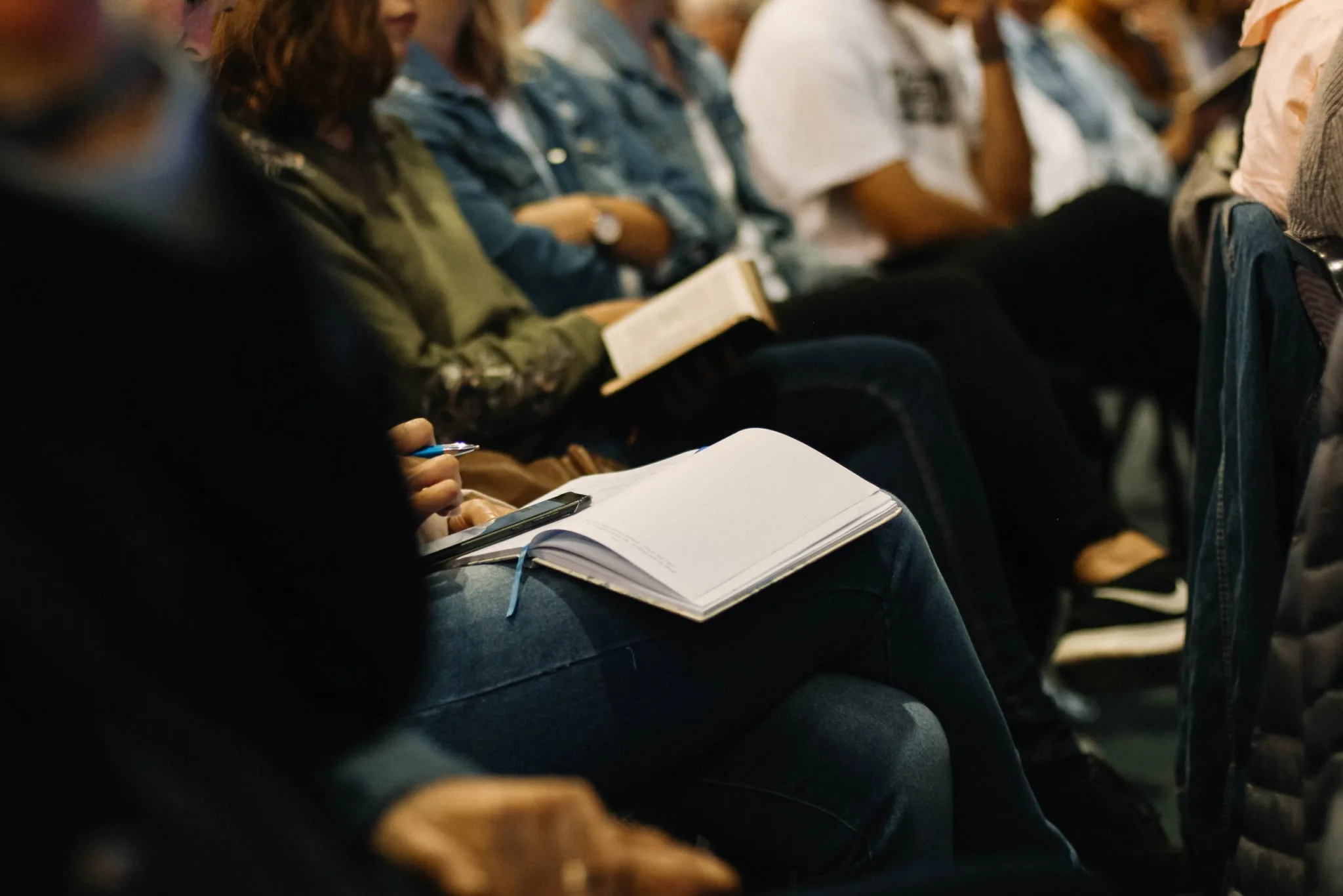 Photo of people sitting in chairs with notebooks on their laps.